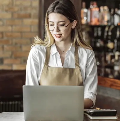 Image of a restaurant worker working on a laptop.