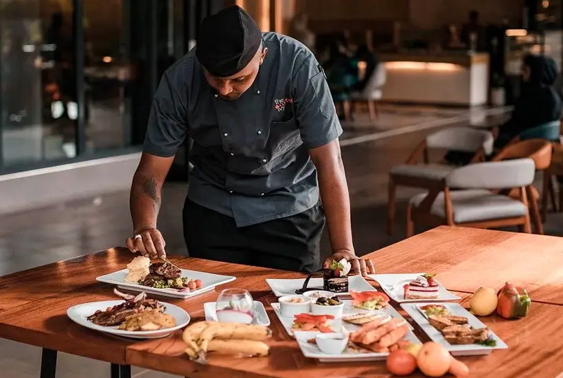 Image of a chef in a restaurant adjusitng the detials of a plating of food.