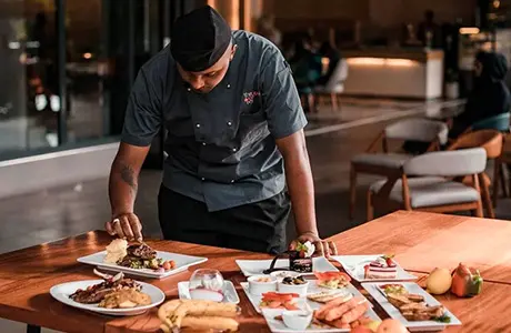 Image of a chef in a restaurant adjusitng the detials of a plating of food.