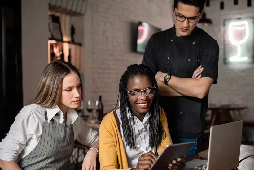 Image of a group of smiling kitchen workers standing side by side.