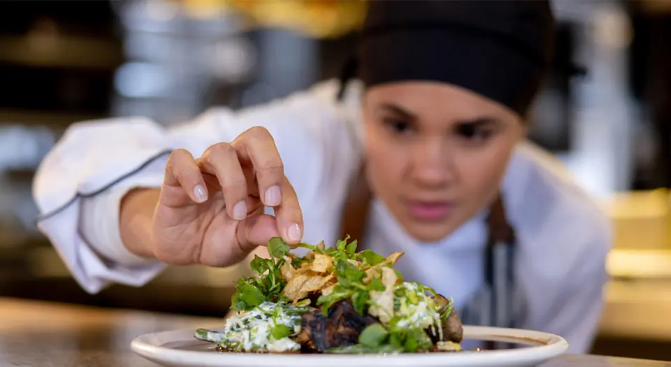 A chef adding a small detial to an entree plating.