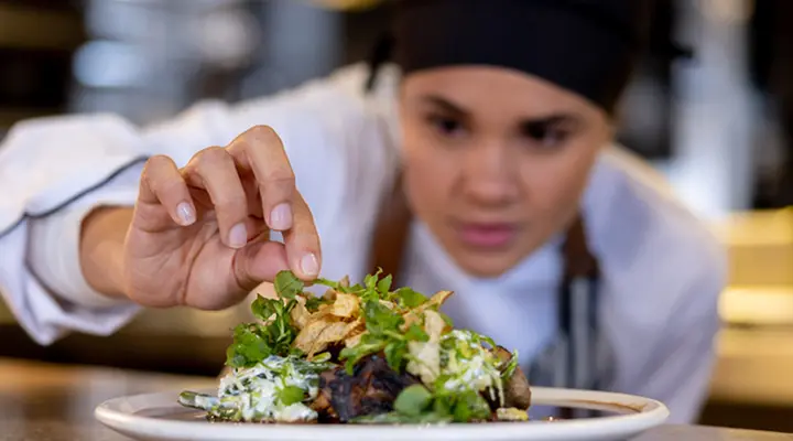 A chef adding a small detial to an entree plating.