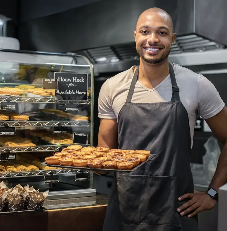Food handler proudly holding a tray of fresh baked goods